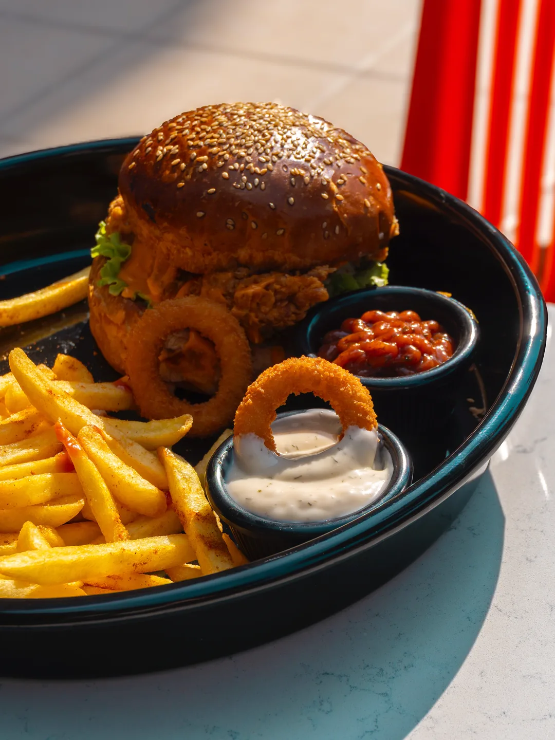 Tabakta burger, soğan halkaları ve patates kızartması