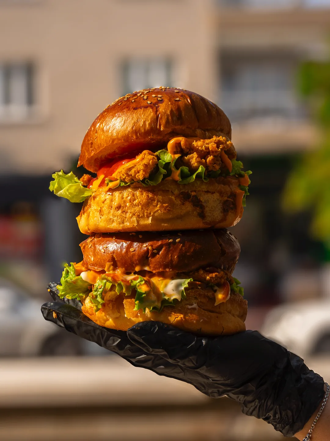 Siyah eldivenli elde iki katlı çıtır tavuklu burger