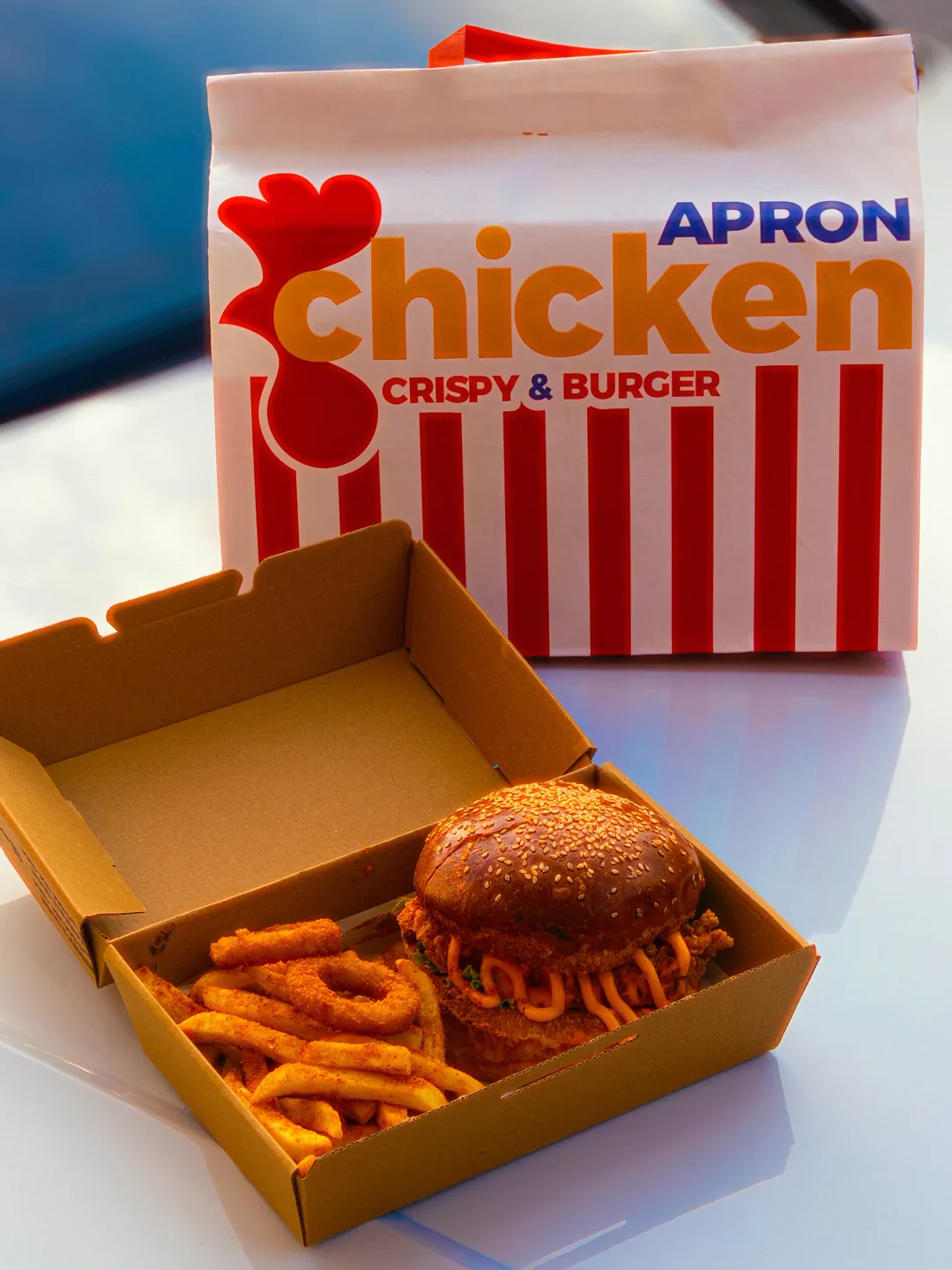 Apron Chicken paket kutusu, içinde burger ve soğan halkaları